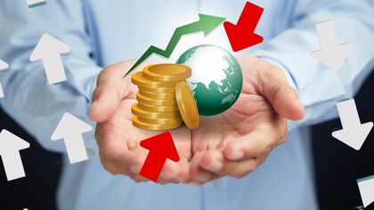 Imagen de unas manos sosteniendo un gráfico de un mundo y monedas
