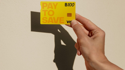 Mano sosteniendo la tarjeta B100 Pay to Save amarilla con chip, fabricada con materiales reciclados