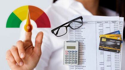 Imagen de una mano señalando una rueda de niveles y figuras de calculadora y tarjetas de crédito.