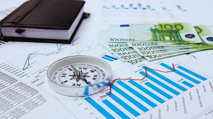 Imagen con una brújula, billetes de euros y gráficos impresos. Imagen con una brújula, billetes de euros y gráficos impresos.