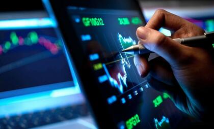 Imagen de una mano analizando gráficos financieros en una pantalla, representando la interpretación profesional del contexto del mercado.