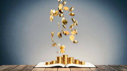 Monedas de oro cayendo sobre un libro de trading