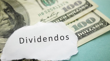 La palabra dividendos encima de dos billetes de 100 dólares